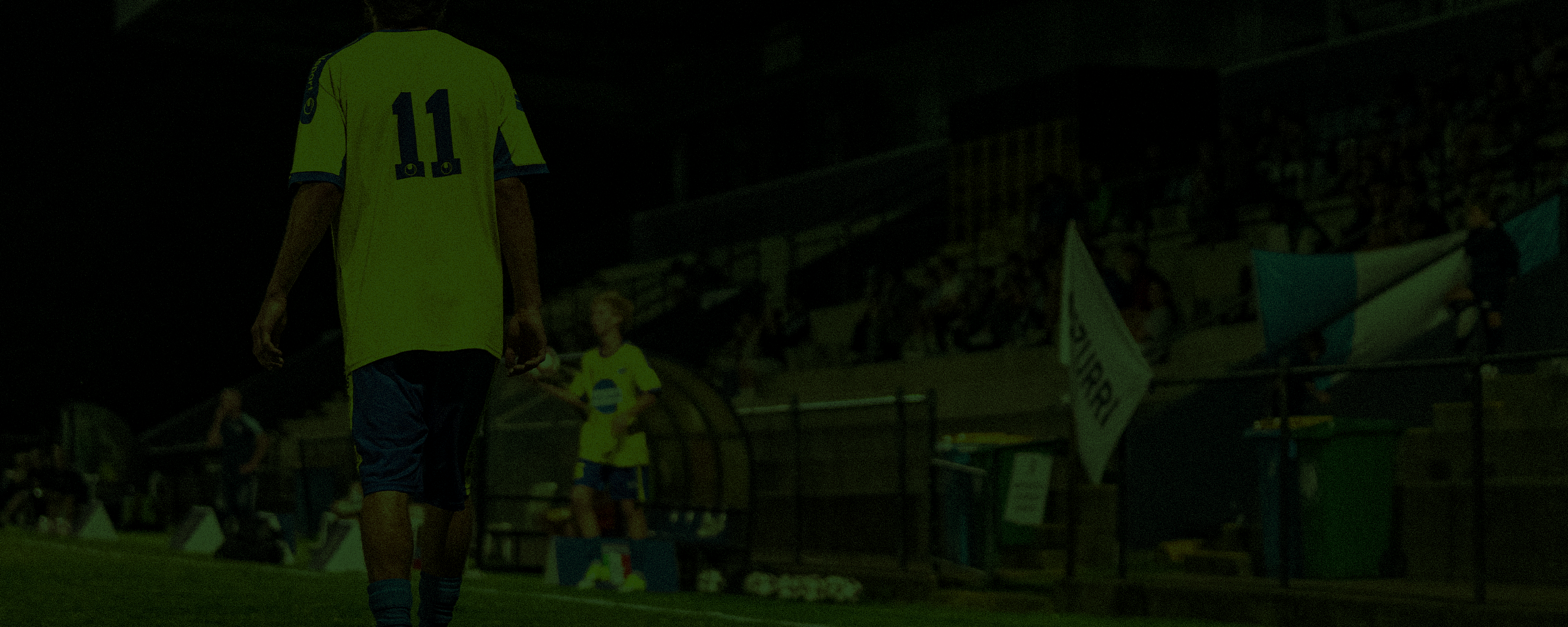 Footballer walking along the sideline at night